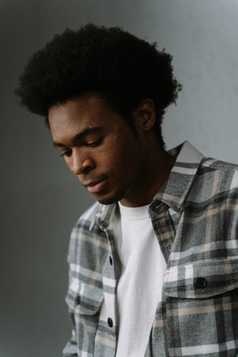 Close-Up Shot of an Afro-Haired Man in Checkered Shirt Looking Down